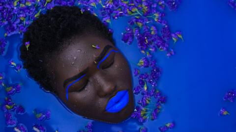 Eine Frau mit blau geschminkten Lippen nimmt ein Bad