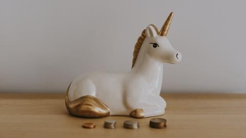 Eine Einhorn-Spardose steht umgeben von Münzen auf einem Tisch