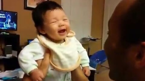 Ce bébé âgé de quelques mois a son premier fou rire. Et son père a bien du mal à ne pas l'imiter